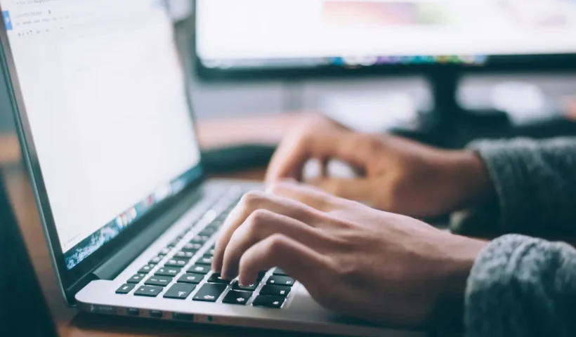 A person typing on a laptop with two hands as a demonstration of how to type faster