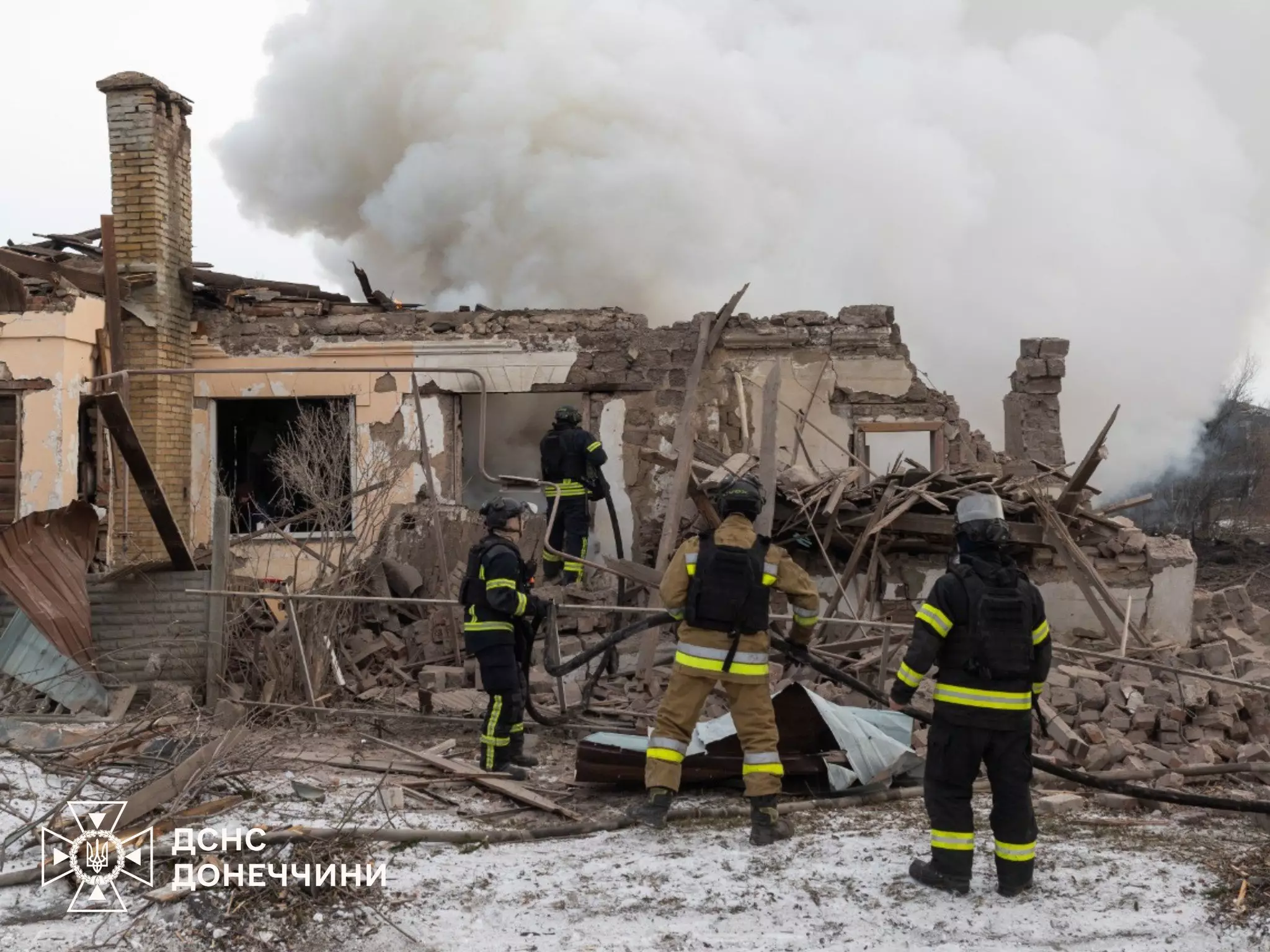Рятувальники оглядають зруйновану будівлю після обстрілу, дим піднімається з-під уламків