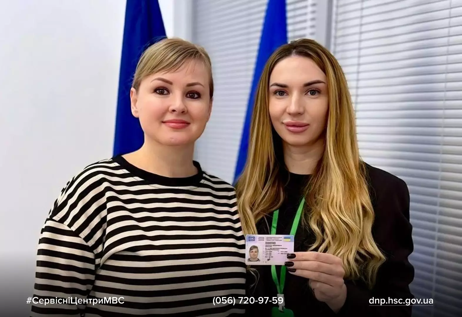 Дві жінки в офісі, одна з них тримає водійське посвідчення, на задньому плані прапори України