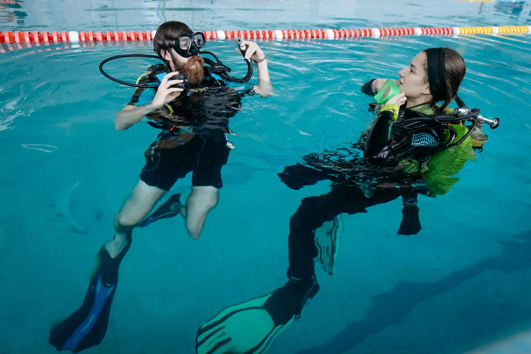 Двоє людей у дайвінг-спорядженні тренуються у басейні для реабілітації ветеранів МВС