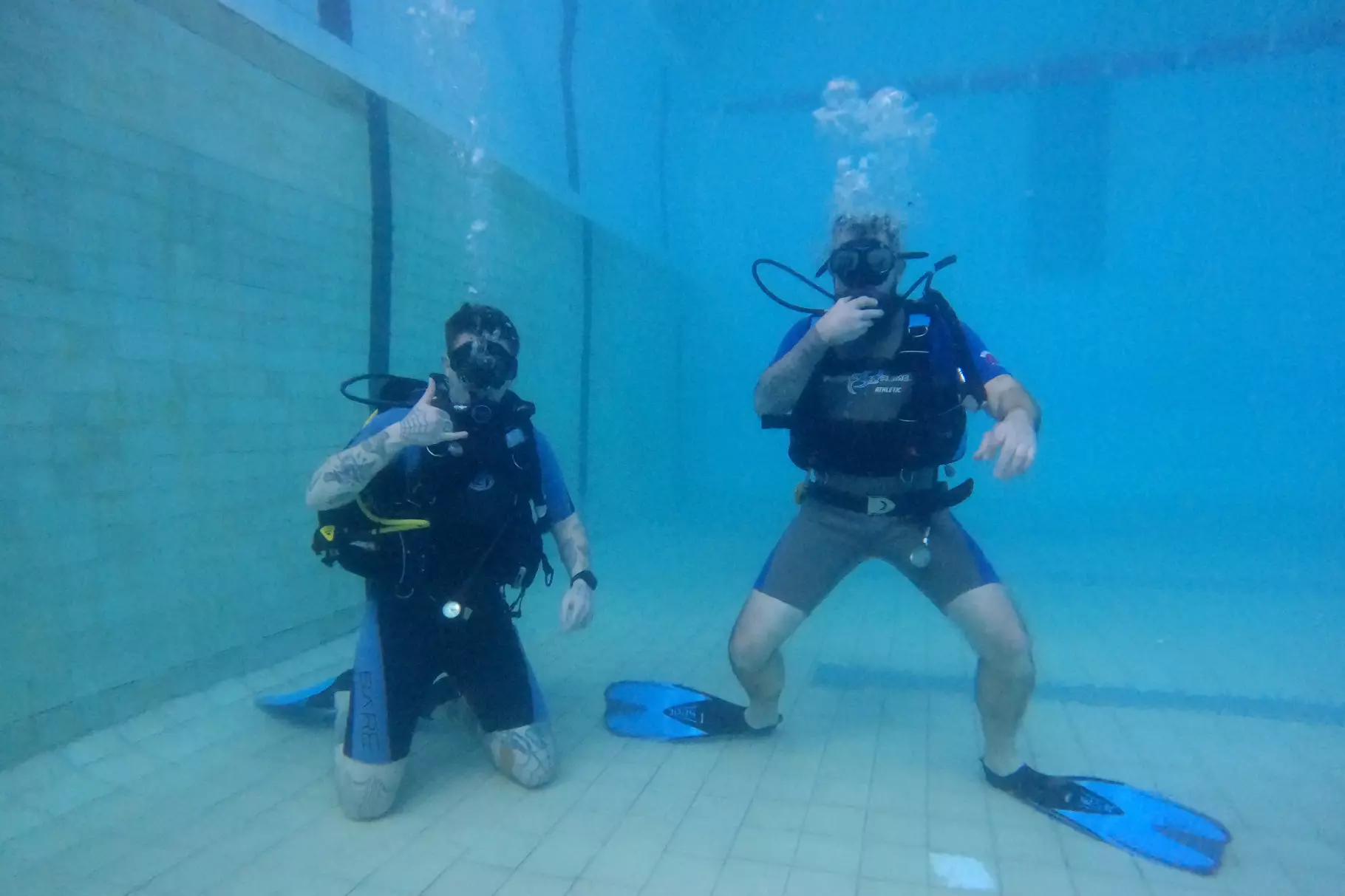 Двоє чоловіків у дайвінг-спорядженні під водою в басейні під час реабілітаційного заняття