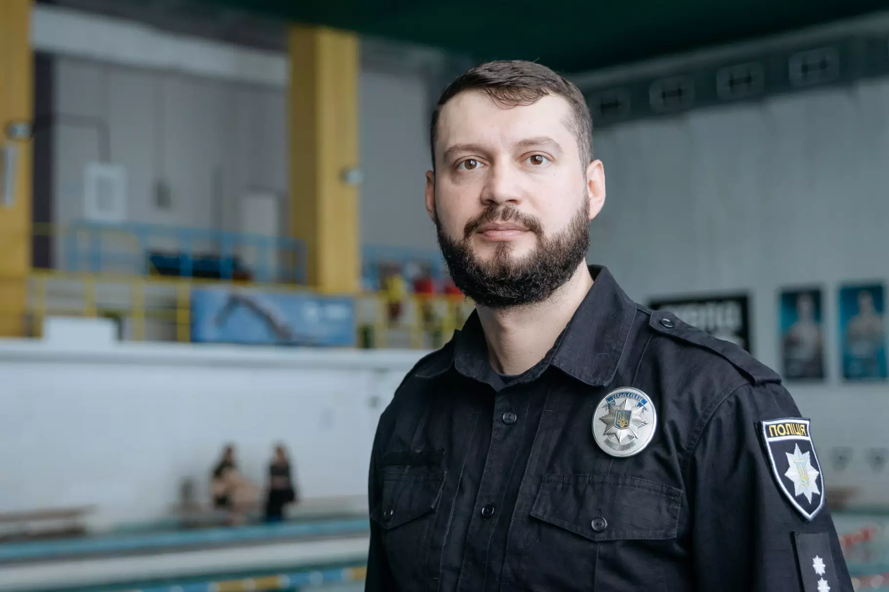 Чоловік у поліцейській формі стоїть біля басейну, де проходять заняття з дайвінгу для ветеранів
