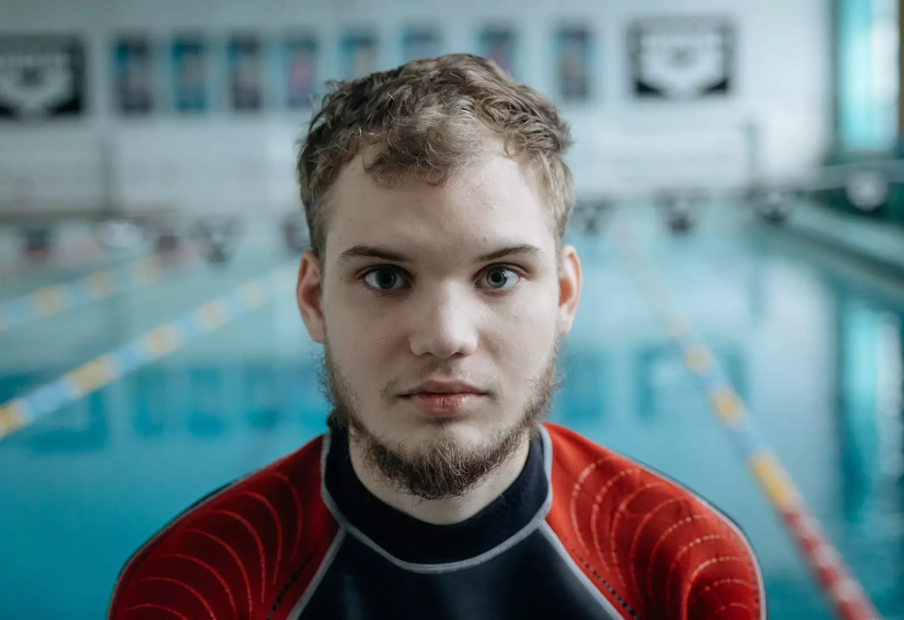 Чоловік у гідрокостюмі стоїть перед басейном, використовуючи дайвінг для реабілітації після поранень