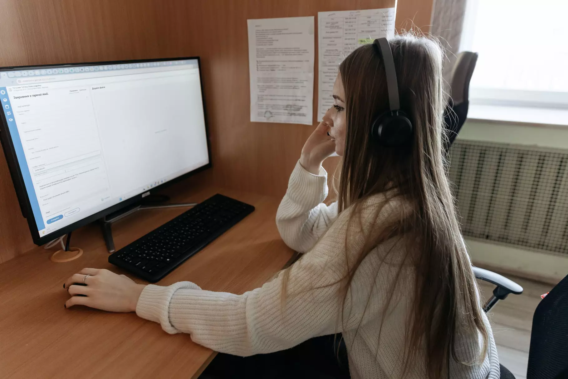 Оператор контакт-центру МВС працює за комп'ютером, приймаючи дзвінки на гарячу лінію