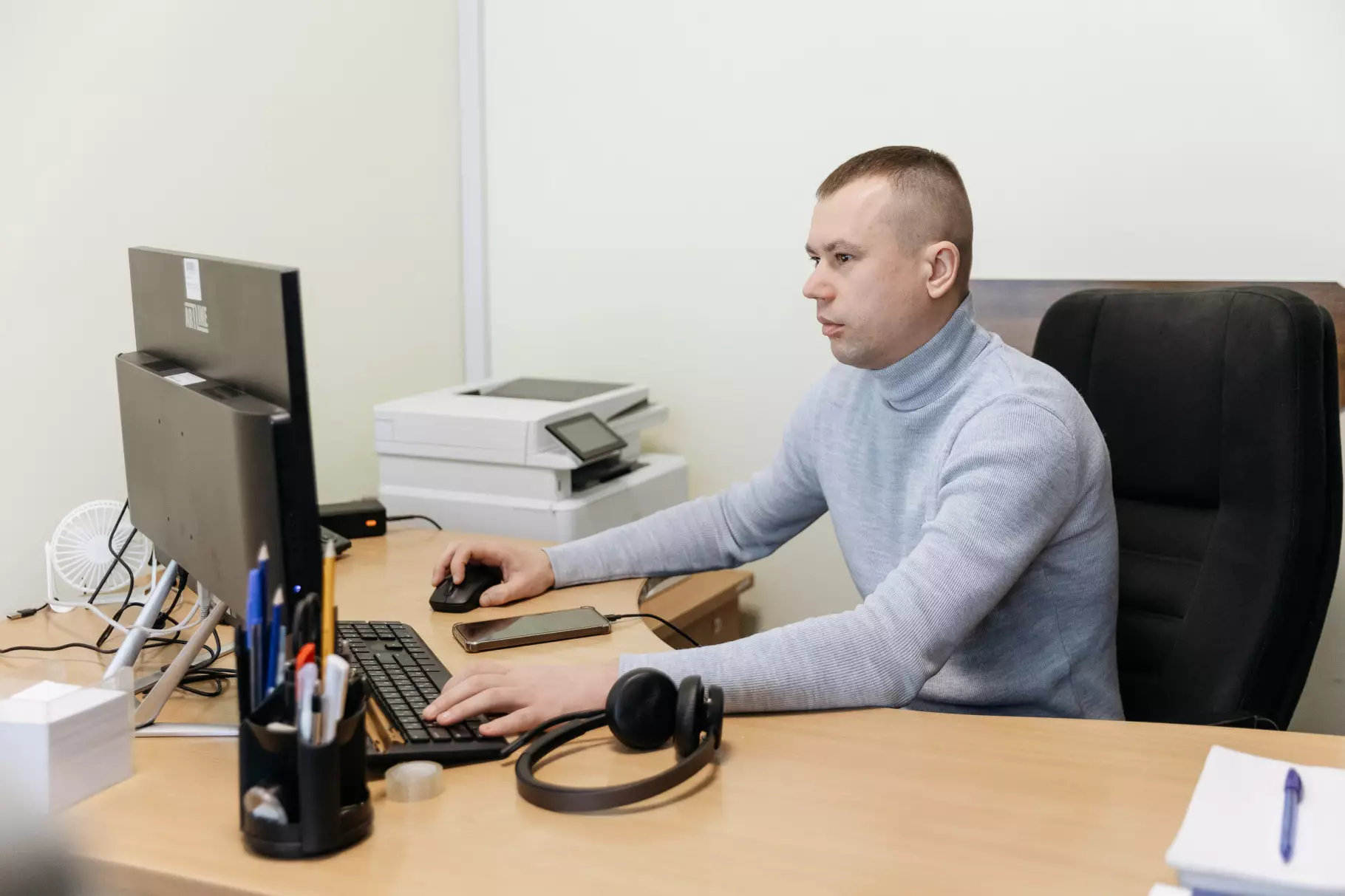 Оператор контактного центру МВС працює за комп'ютером у сучасному офісі, навушники на столі