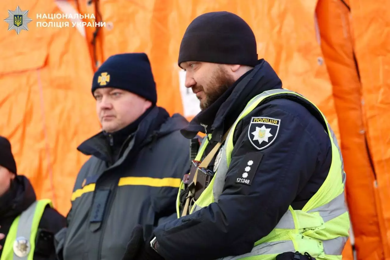 Поліцейські в зимовій формі на тлі помаранчевого намету під час виконання службових обов'язків