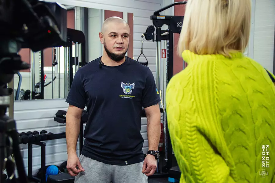 Чоловік у спортивному залі реабілітаційного центру Національної гвардії України спілкується з жінкою