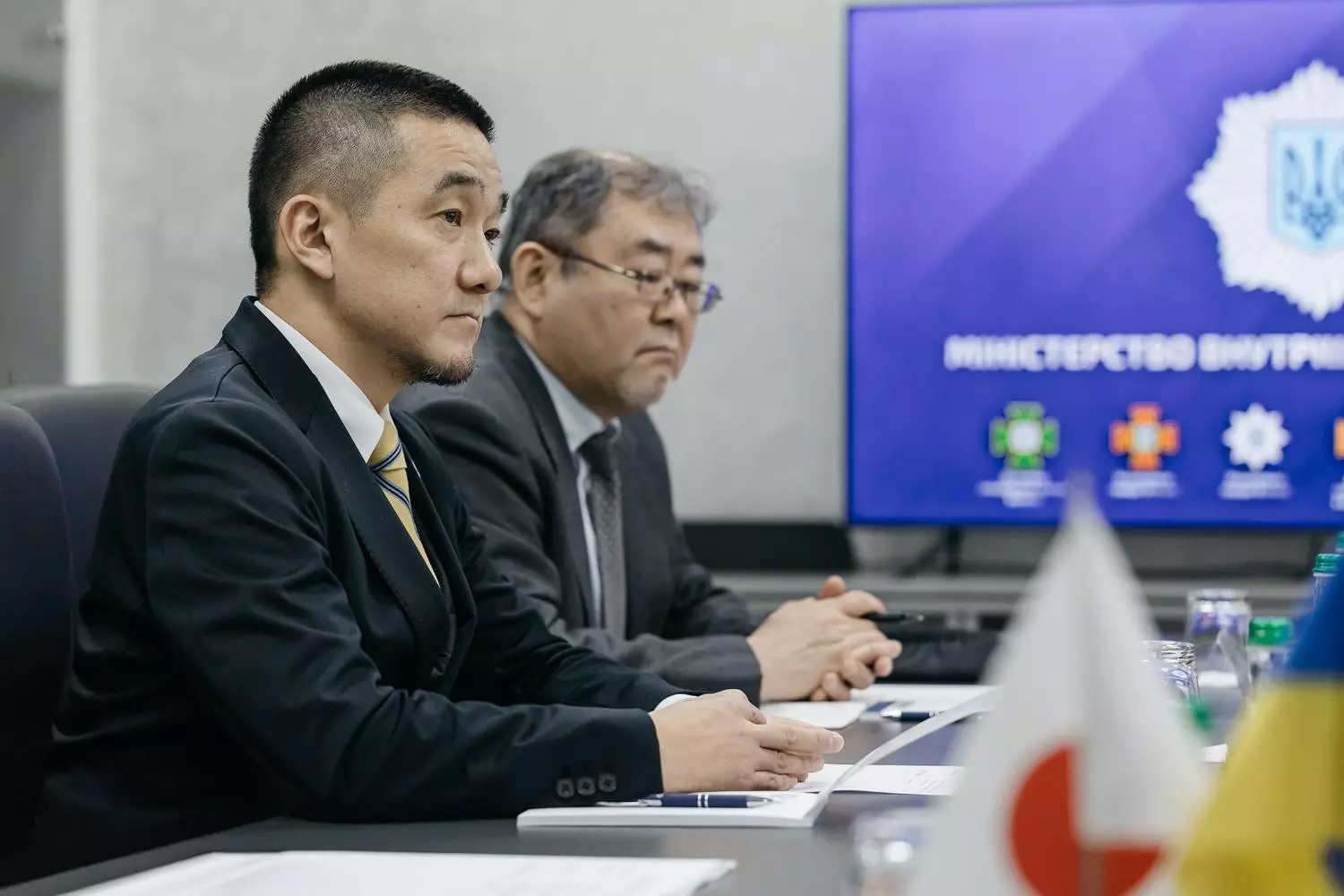 Двоє чоловіків підписують угоду на зустрічі з представниками МВС України та JICA