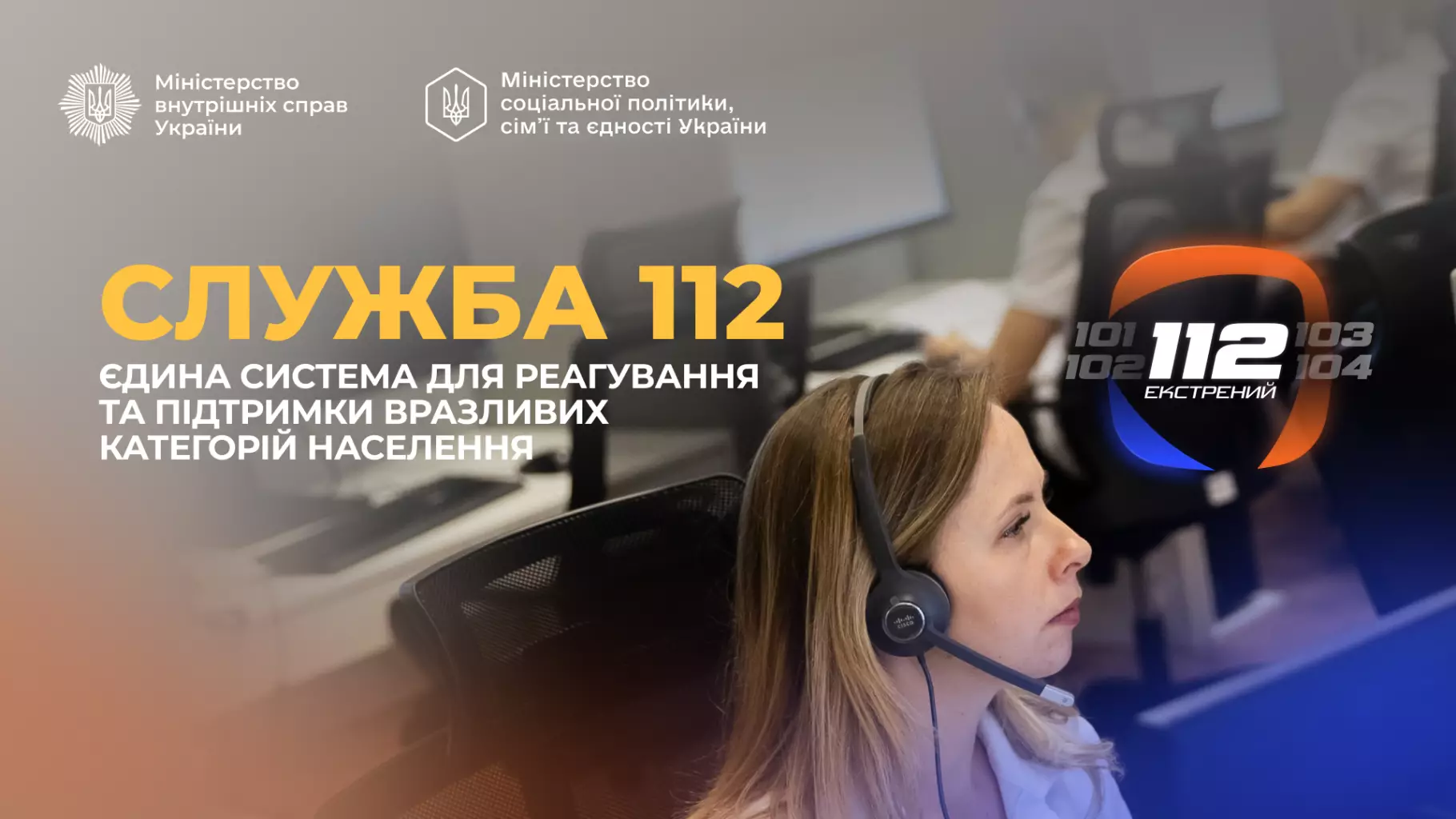 Операторка служби 112 в навушниках працює в офісі, на задньому плані екрани комп'ютерів