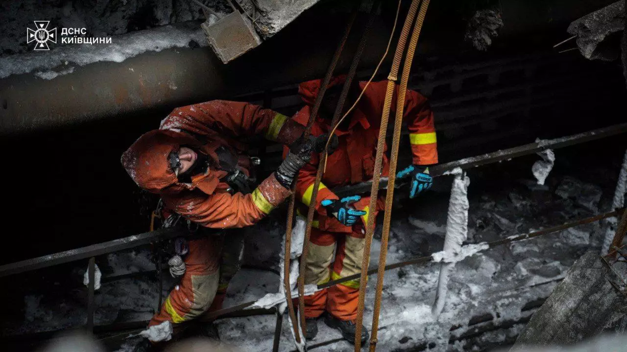 Рятувальники-верхолази в захисному одязі працюють на висоті серед пошкоджених конструкцій під час зими