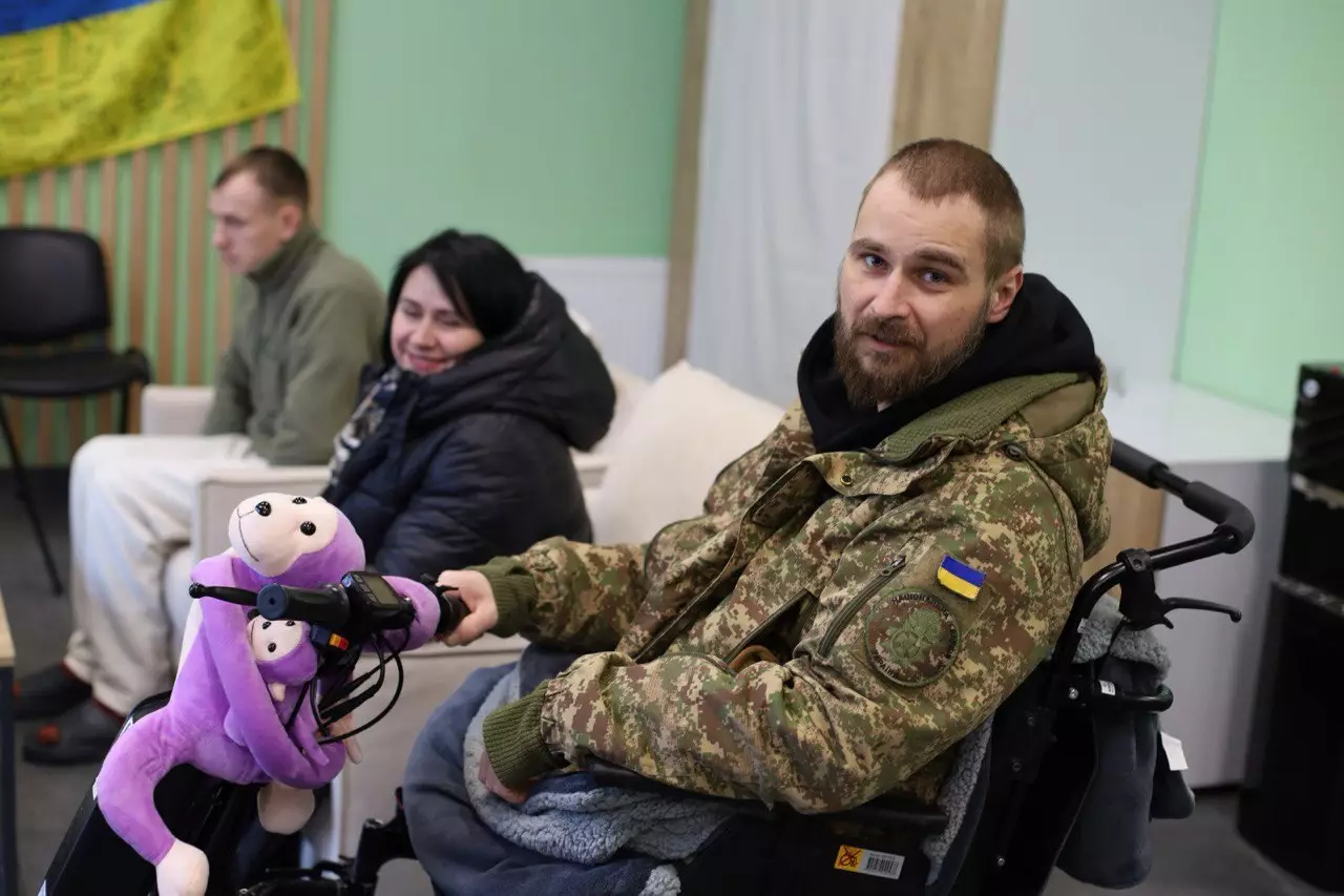 Ветеран у військовій формі на інвалідному візку з іграшкою, отримує підтримку в сервісному центрі МВС