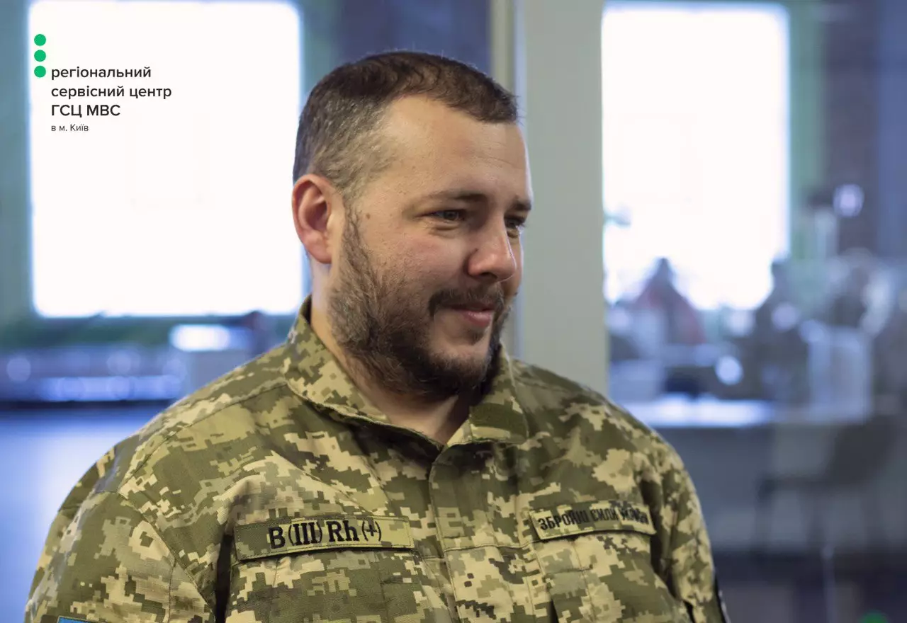 Чоловік у військовій формі в офісі сервісного центру МВС, на задньому плані розмитий інтер'єр