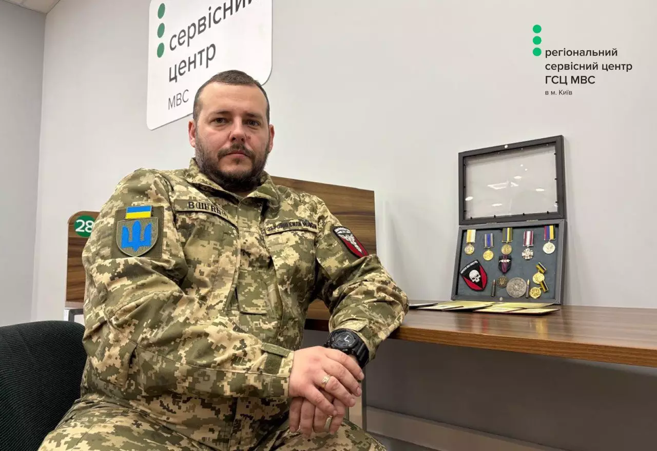 Ветеран у військовій формі сидить у сервісному центрі МВС поруч із нагородами на столі