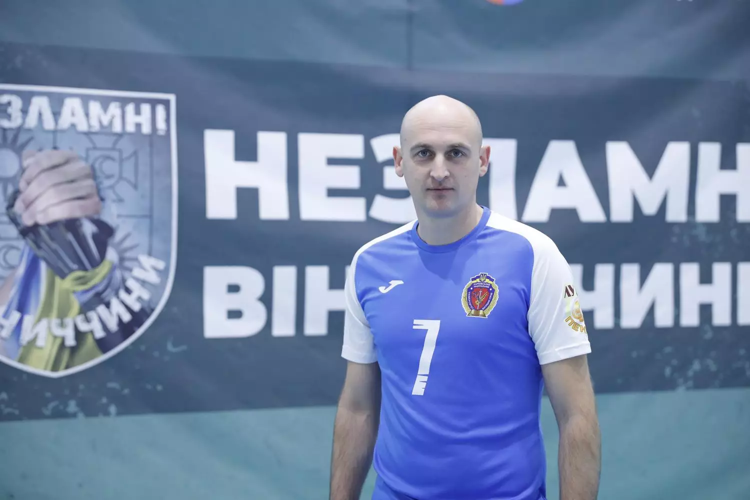 Ветеран у спортивній формі стоїть перед банером з написом "Незламні Вінничини