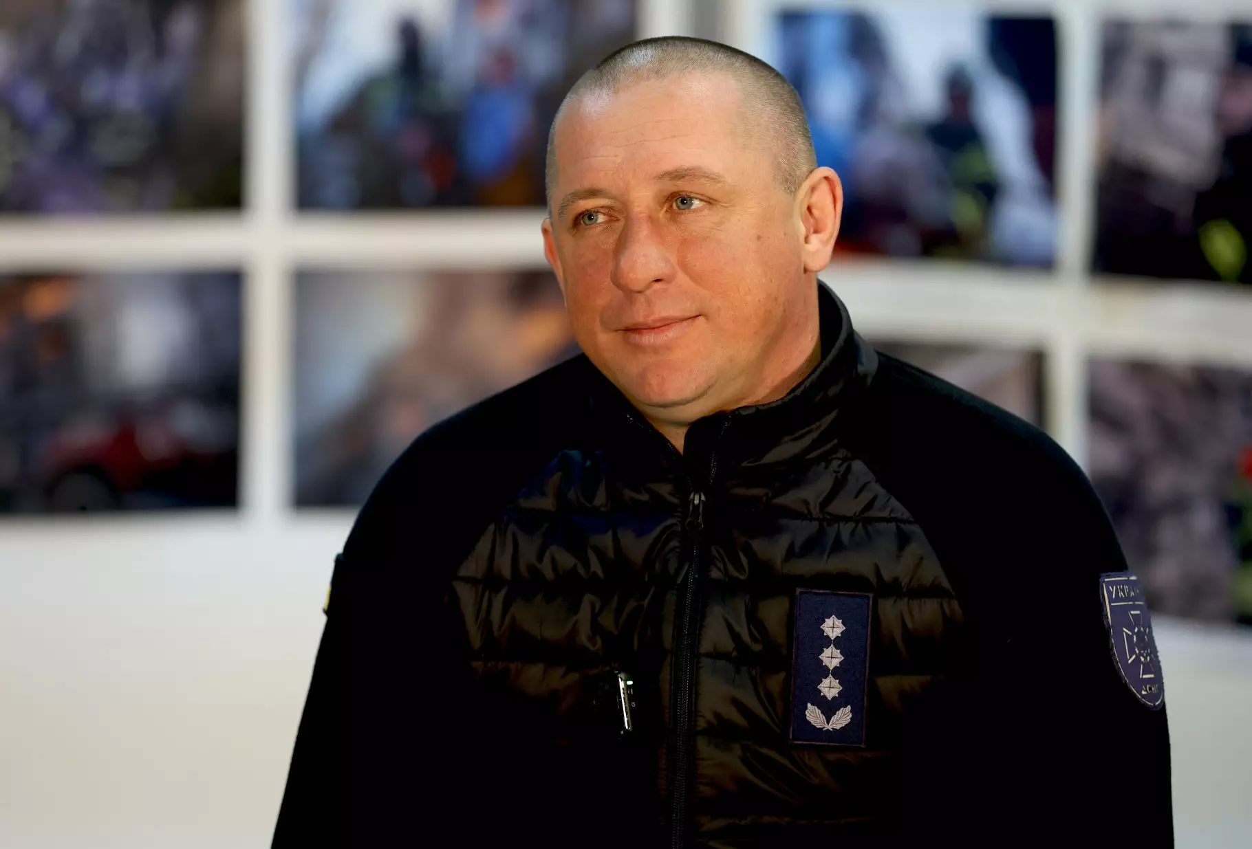 Рятувальник ДСНС у чорній куртці на фоні фотографій з підводної операції в умовах сильного морозу