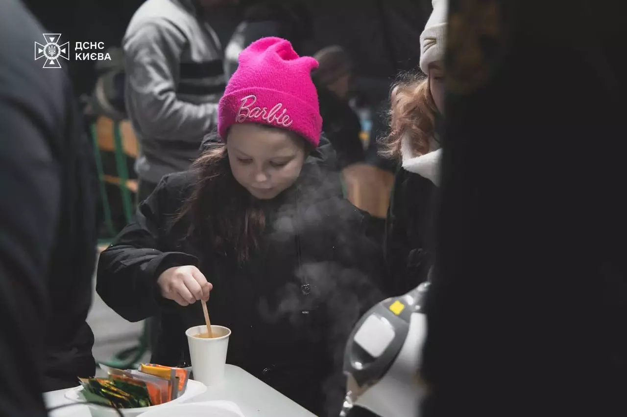 Дитина в рожевій шапці готує гарячий напій у пункті обігріву ДСНС Києва