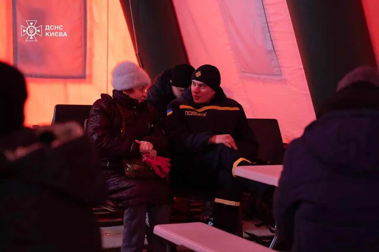 Пункт обігріву ДСНС у наметі, рятувальник спілкується з літньою жінкою, забезпечуючи допомогу