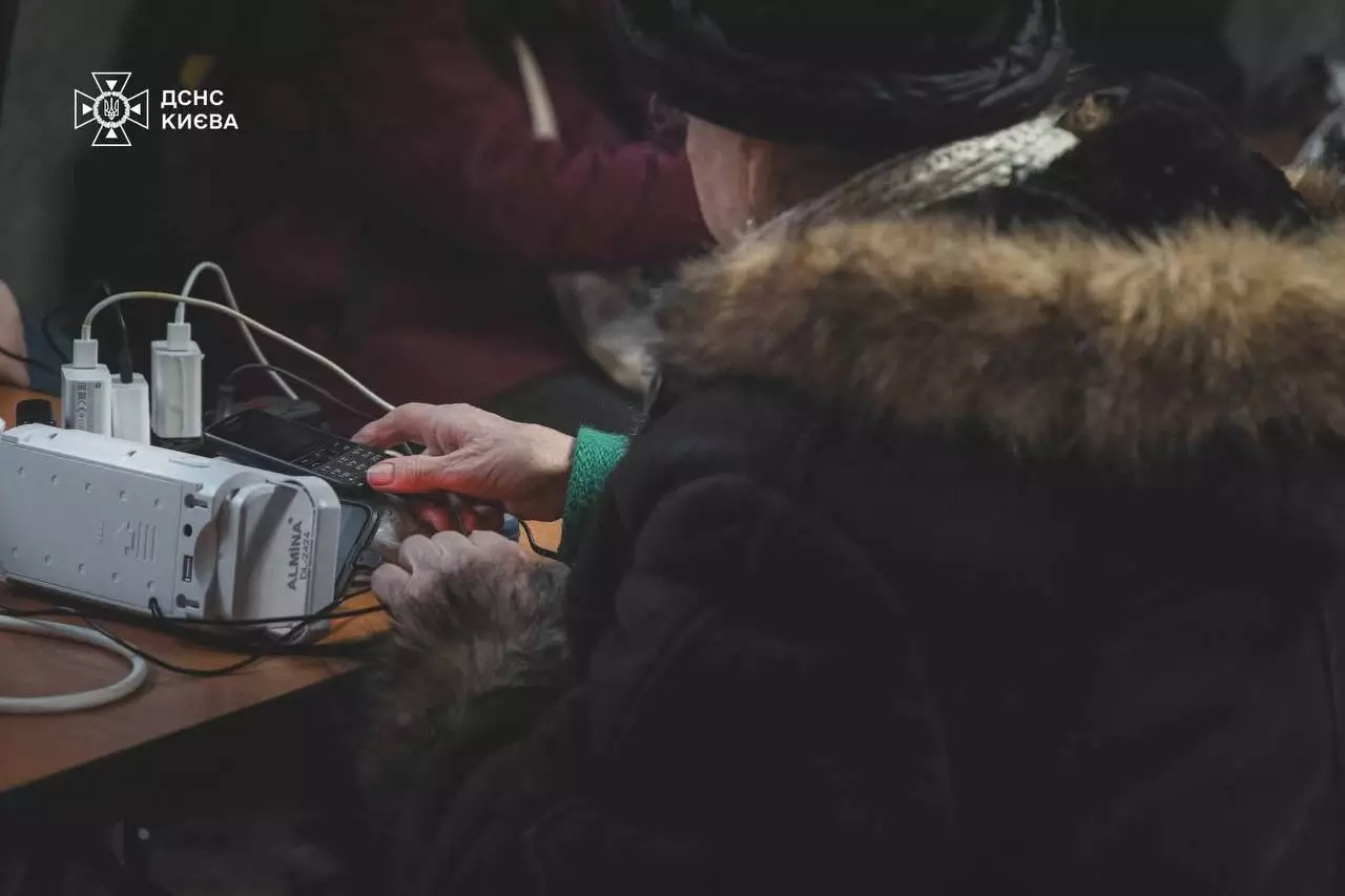 Людина заряджає телефон у пункті обігріву, забезпеченому генератором, організованому МВС України
