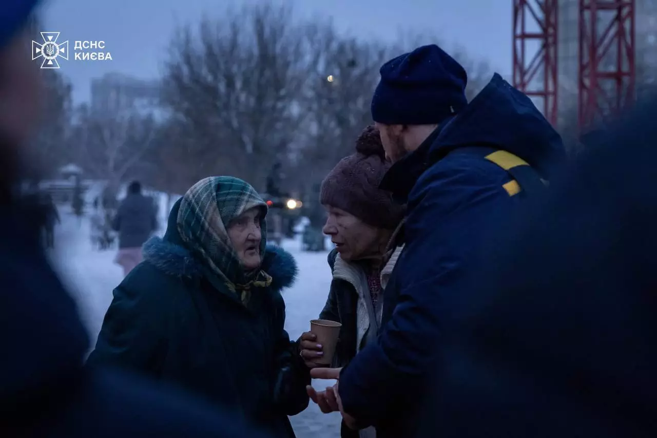 Люди в зимовому одязі спілкуються на вулиці біля пункту обігріву ДСНС у Києві