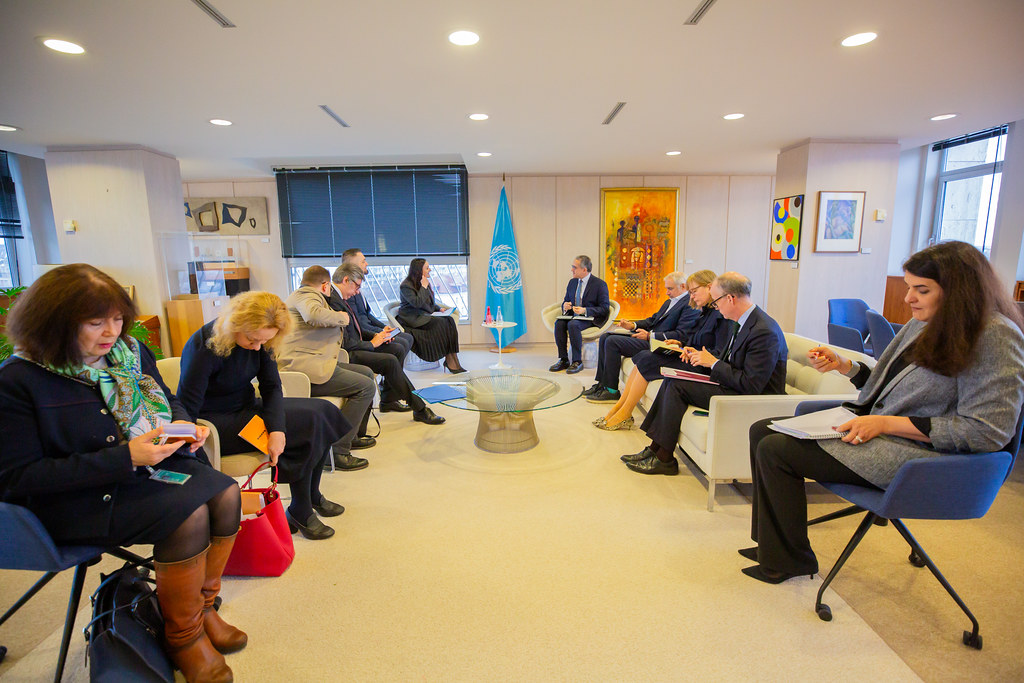 Учасники зустрічі сидять у залі з прапором ЮНЕСКО, обговорюючи питання культурної співпраці