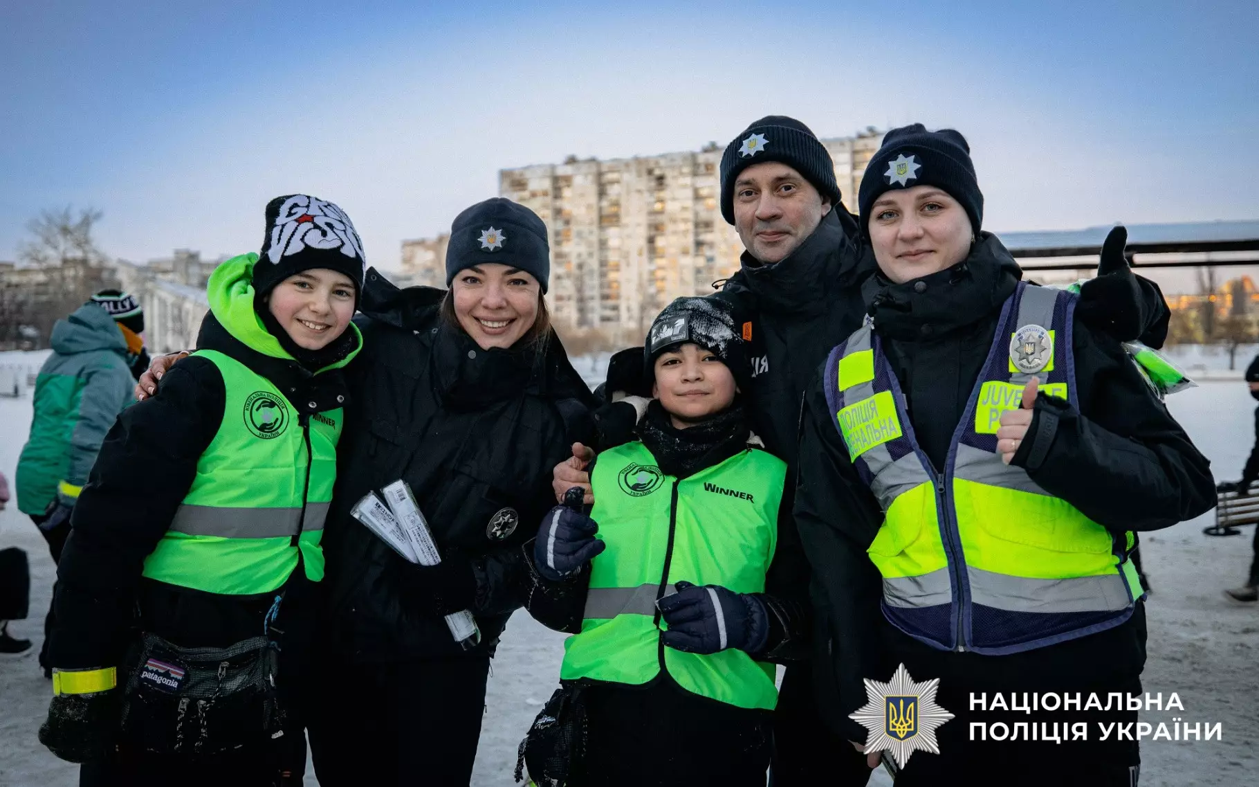 Ювенальні поліцейські з дітьми на зимовій прогулянці, роздають світловідбивальні елементи для безпеки