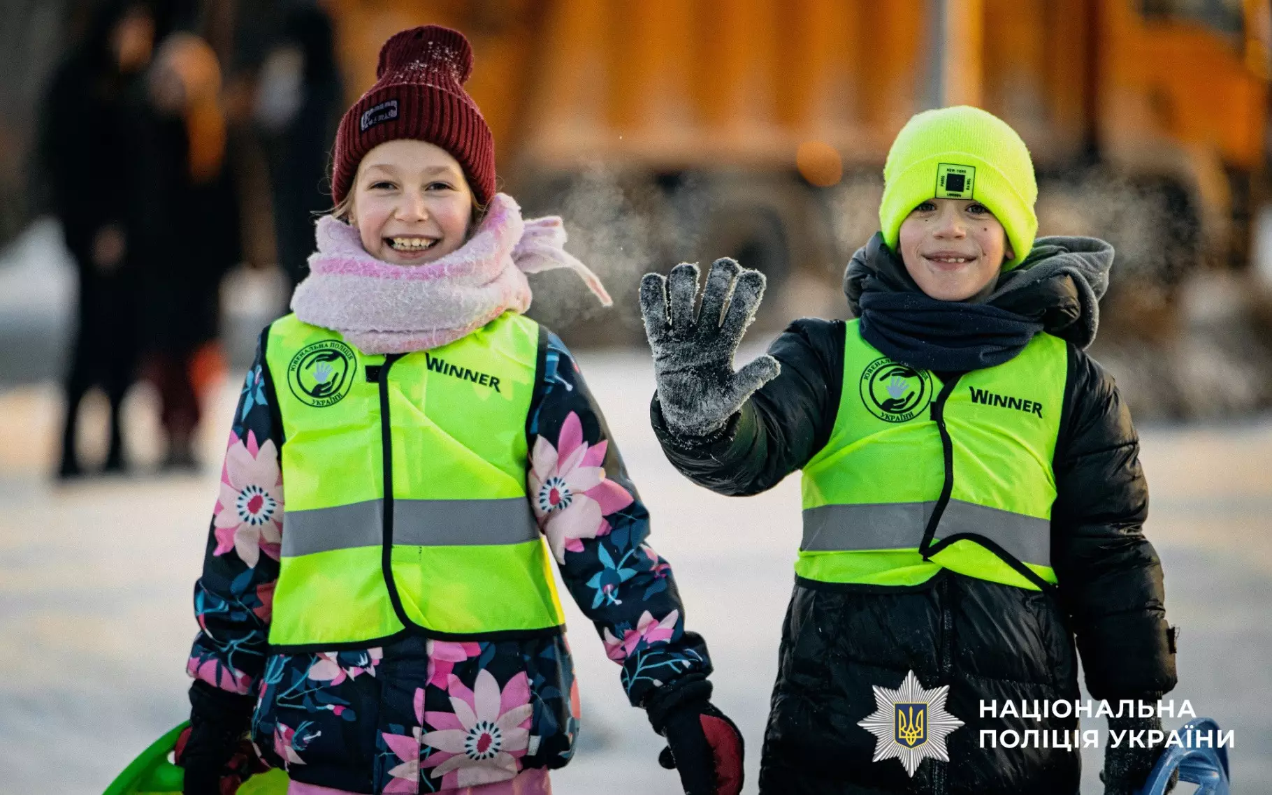 Діти в яскравих жилетах зі світловідбивальними елементами під час зимових розваг на вулиці