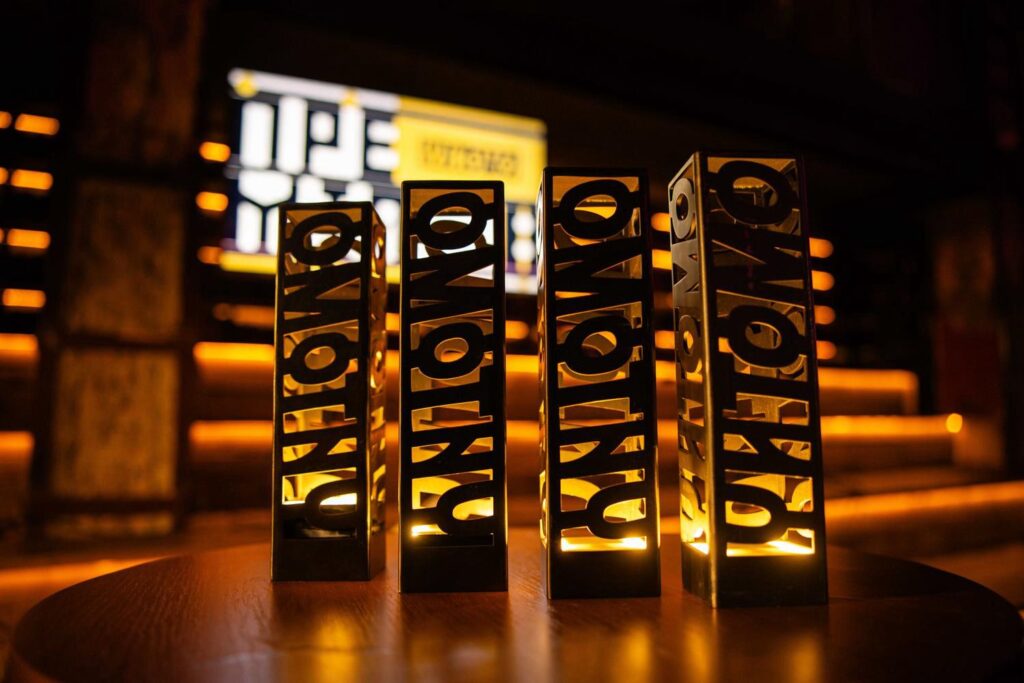 Чотири нагороди Премії Читомо на дерев'яному столі з підсвіткою на фоні сцени