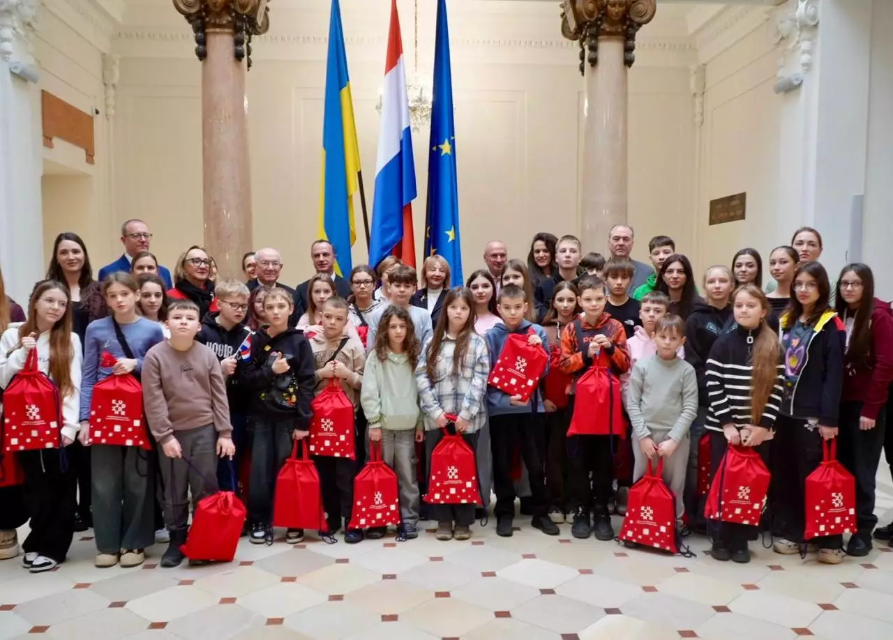 Діти з України з червоними сумками на фоні прапорів України, Хорватії та ЄС у Загребі