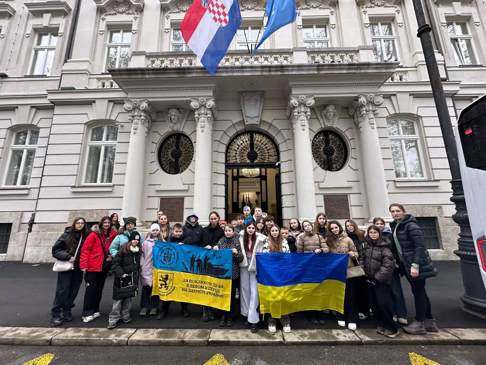 Група дітей з прапорами України та Хорватії перед будівлею в Загребі під час міжнародної програми