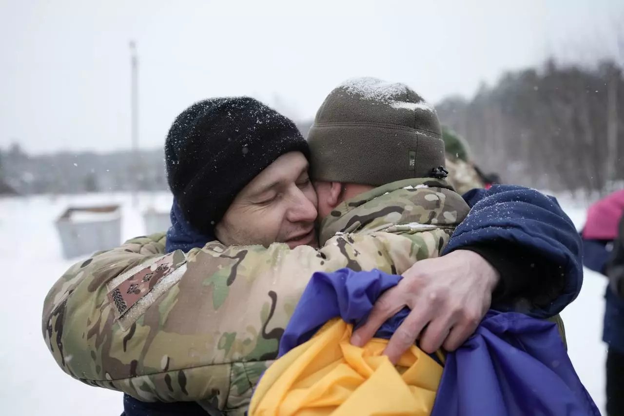 Двоє чоловіків у військовій формі обіймаються на снігу, один тримає український прапор