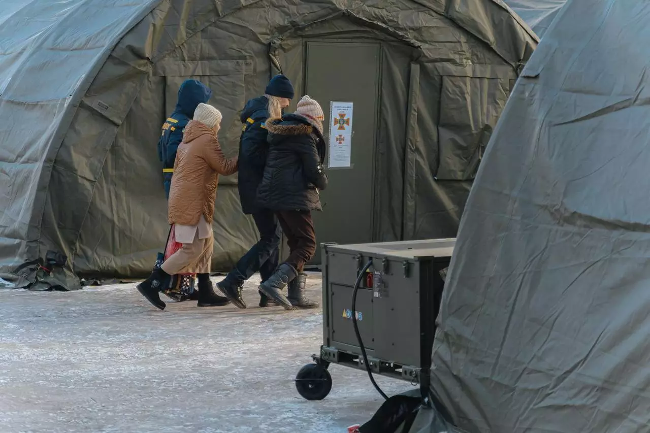 Люди заходять у тимчасовий наметовий пункт обігріву на засніженій території
