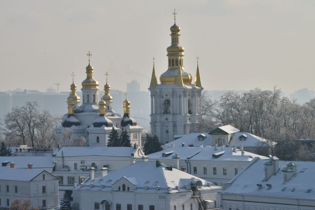 Києво-Печерська лавра взимку, засніжені куполи та будівлі на тлі міського пейзажу