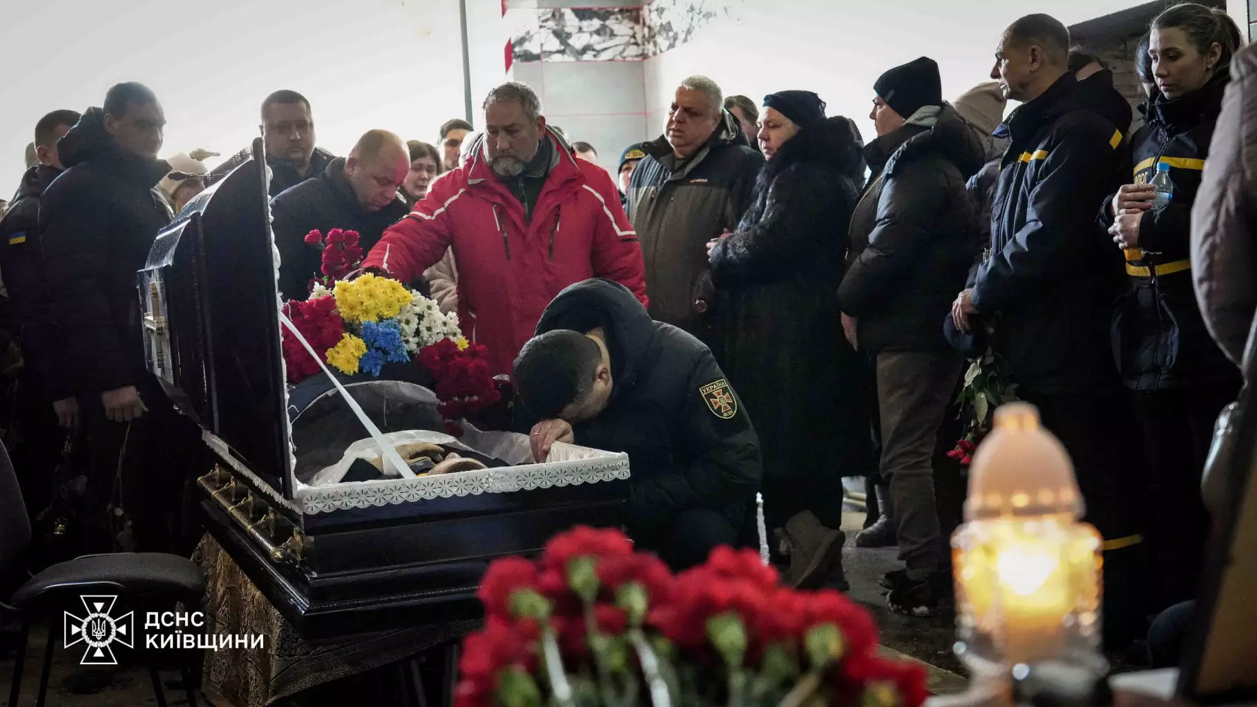 Люди прощаються з рятувальником Михайлом Проценком біля відкритої труни, оточеної квітами