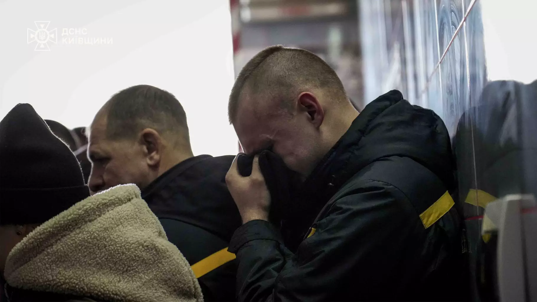 Рятувальники ДСНС України прощаються з колегою, один з них витирає сльози в залі прощання