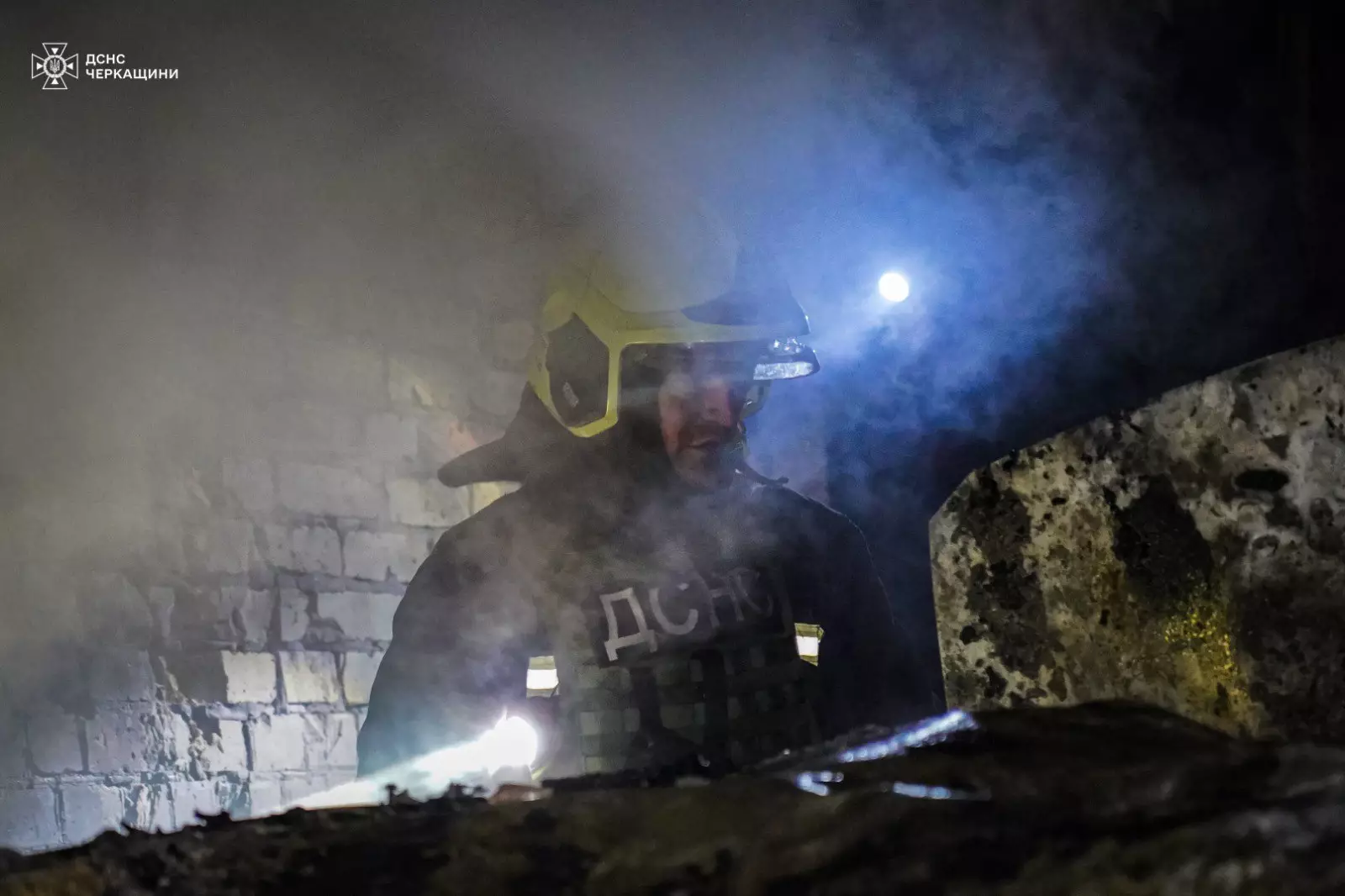 Рятувальник у захисному спорядженні працює серед диму на місці обстрілу в Черкаській області