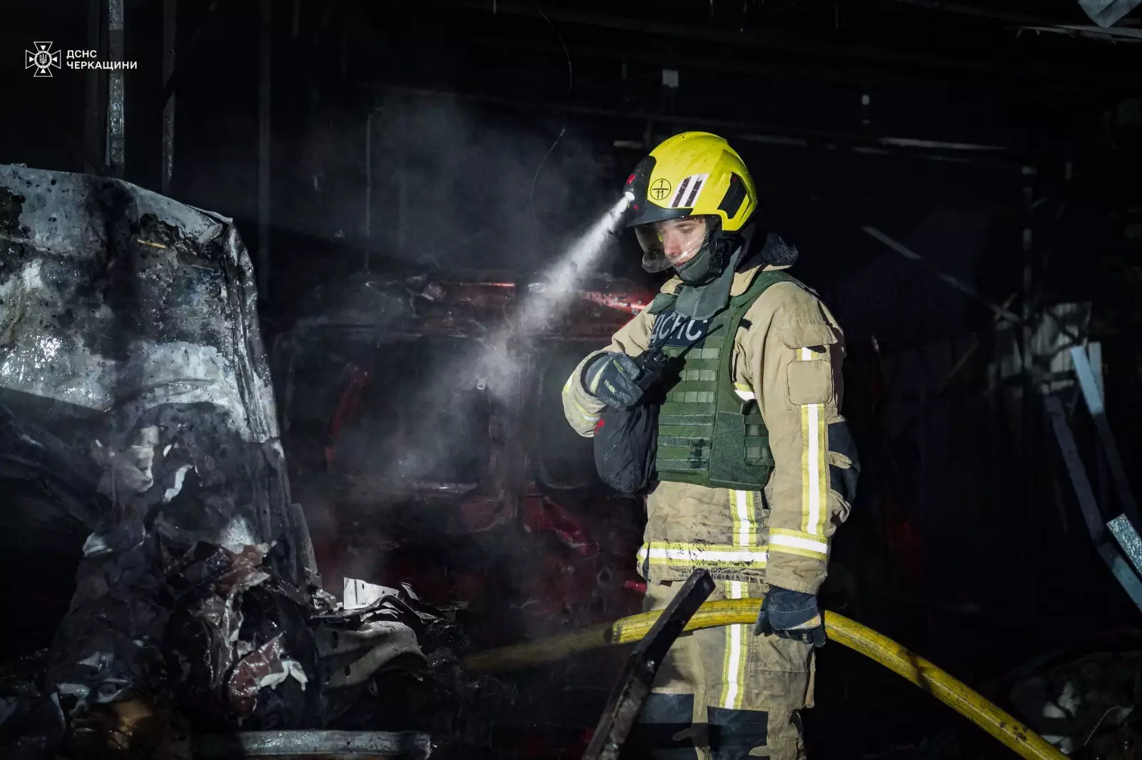 Рятувальник у захисному одязі гасить пожежу в зруйнованій будівлі після обстрілів на Донеччині