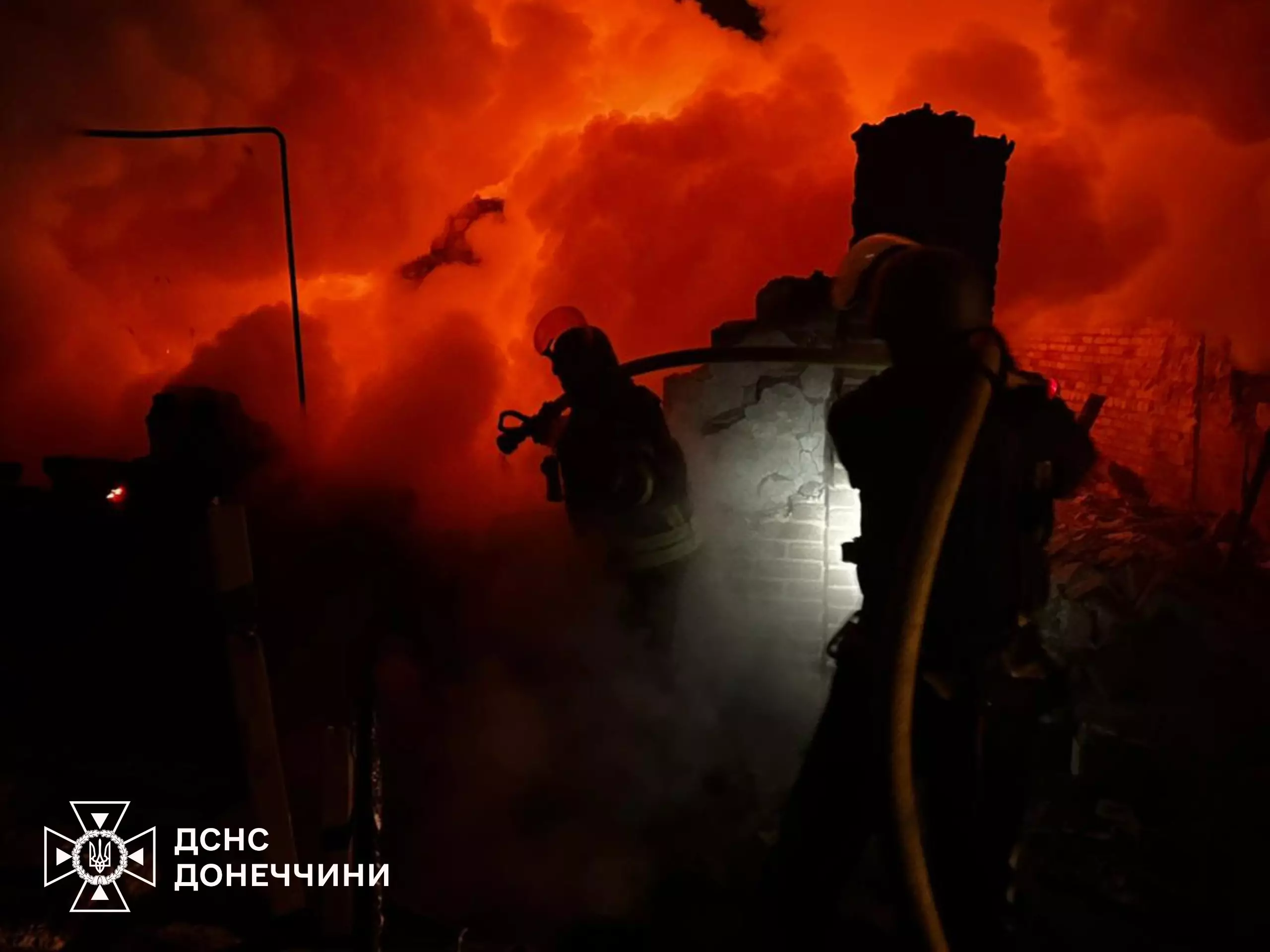 Пожежники гасять вогонь на тлі яскравого полум'я після обстрілів у Донецькій області