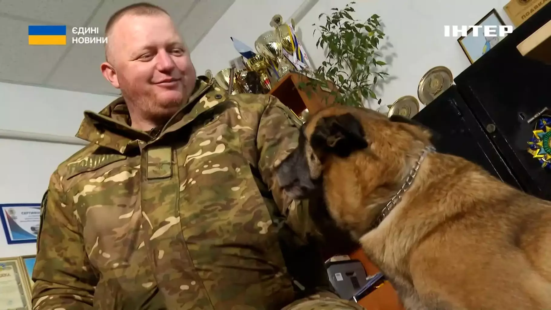 Кінолог у формі спілкується зі службовим собакою в офісі кінологічного центру Національної поліції України