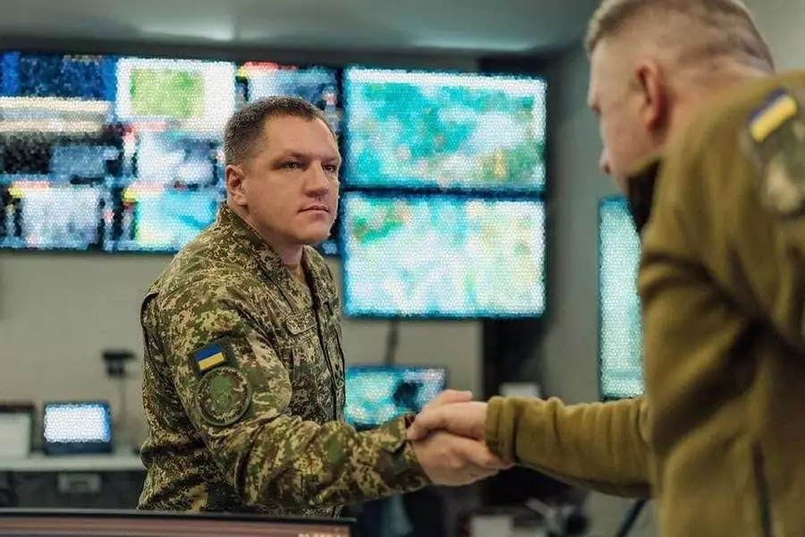 Командувач Нацгвардії України Олександр Півненко тисне руку військовому на фоні екранів з картами