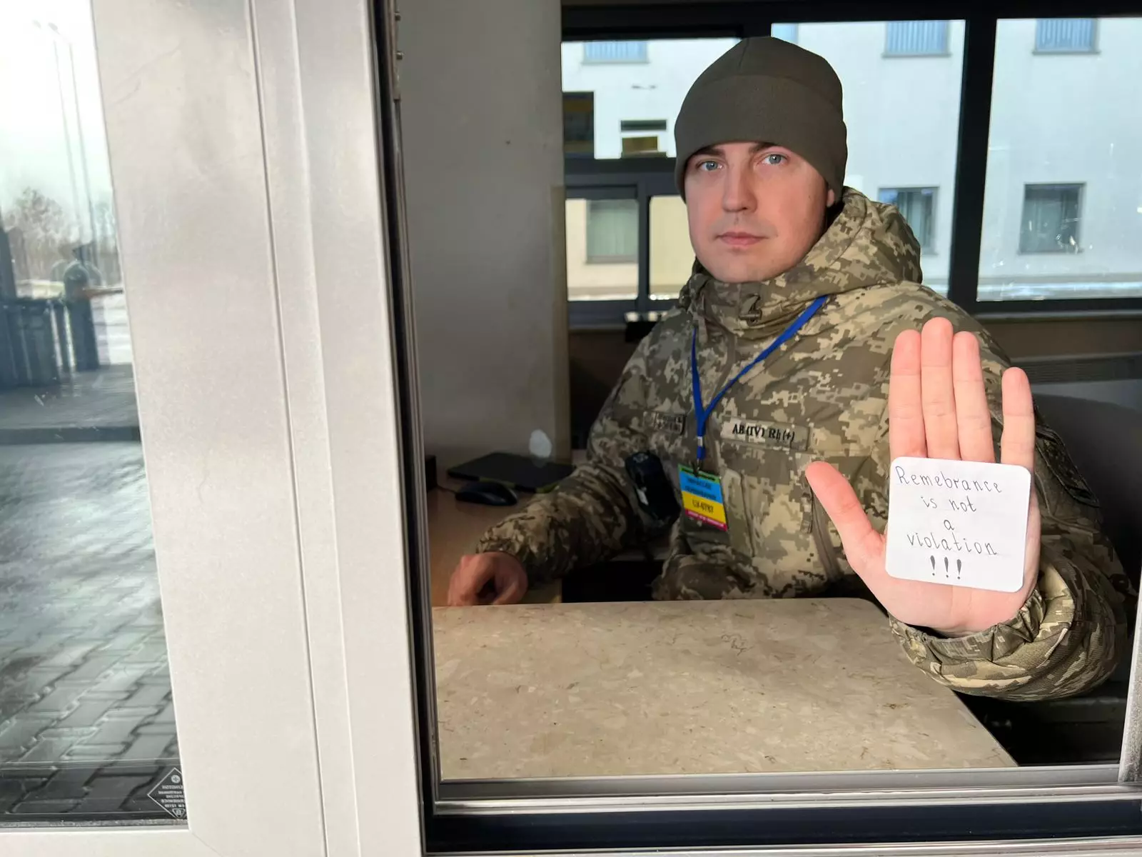 Український прикордонник у військовій формі тримає напис "Remembrance is not a violation" на долоні