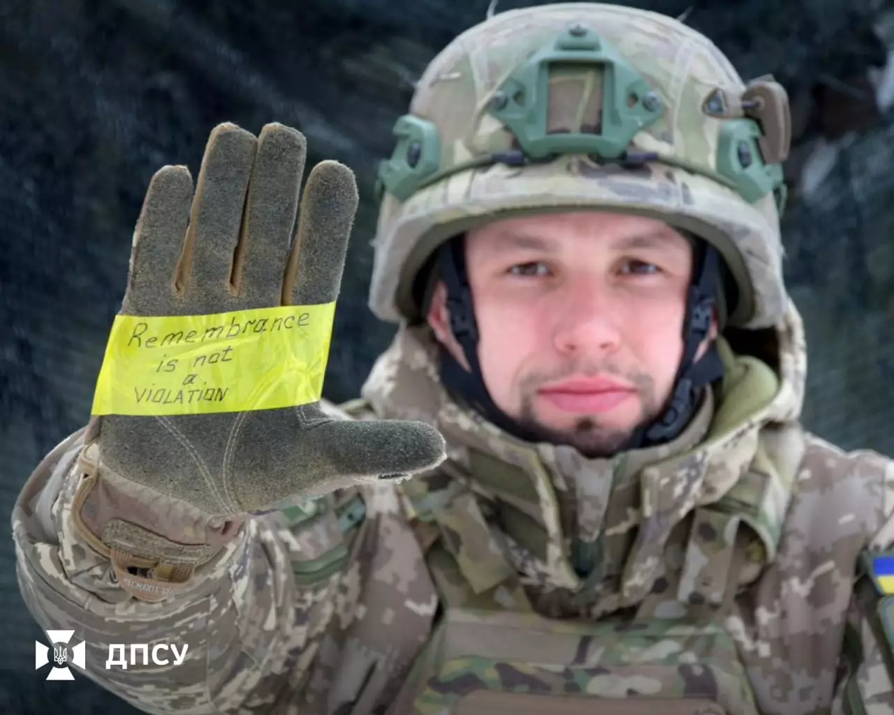Військовослужбовець у формі ДПСУ тримає рукавицю з написом "Remembrance is not a violation