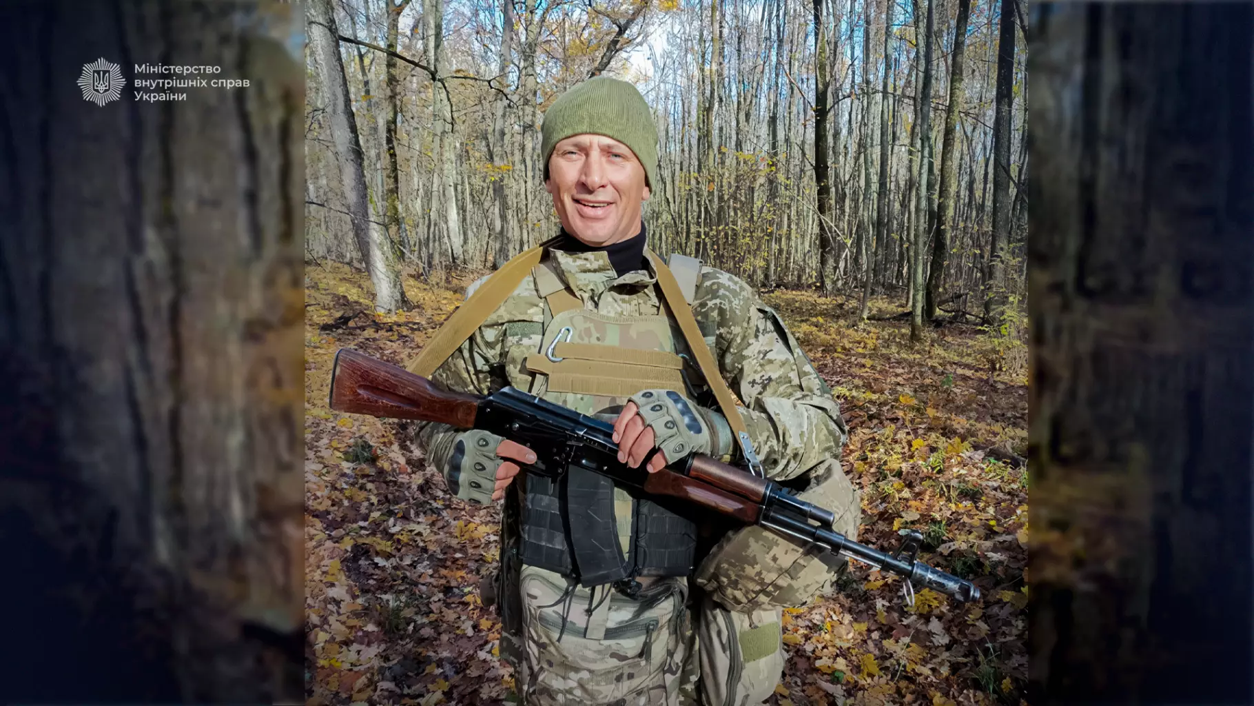 Український військовослужбовець у камуфляжі з автоматом у руках стоїть у лісі восени