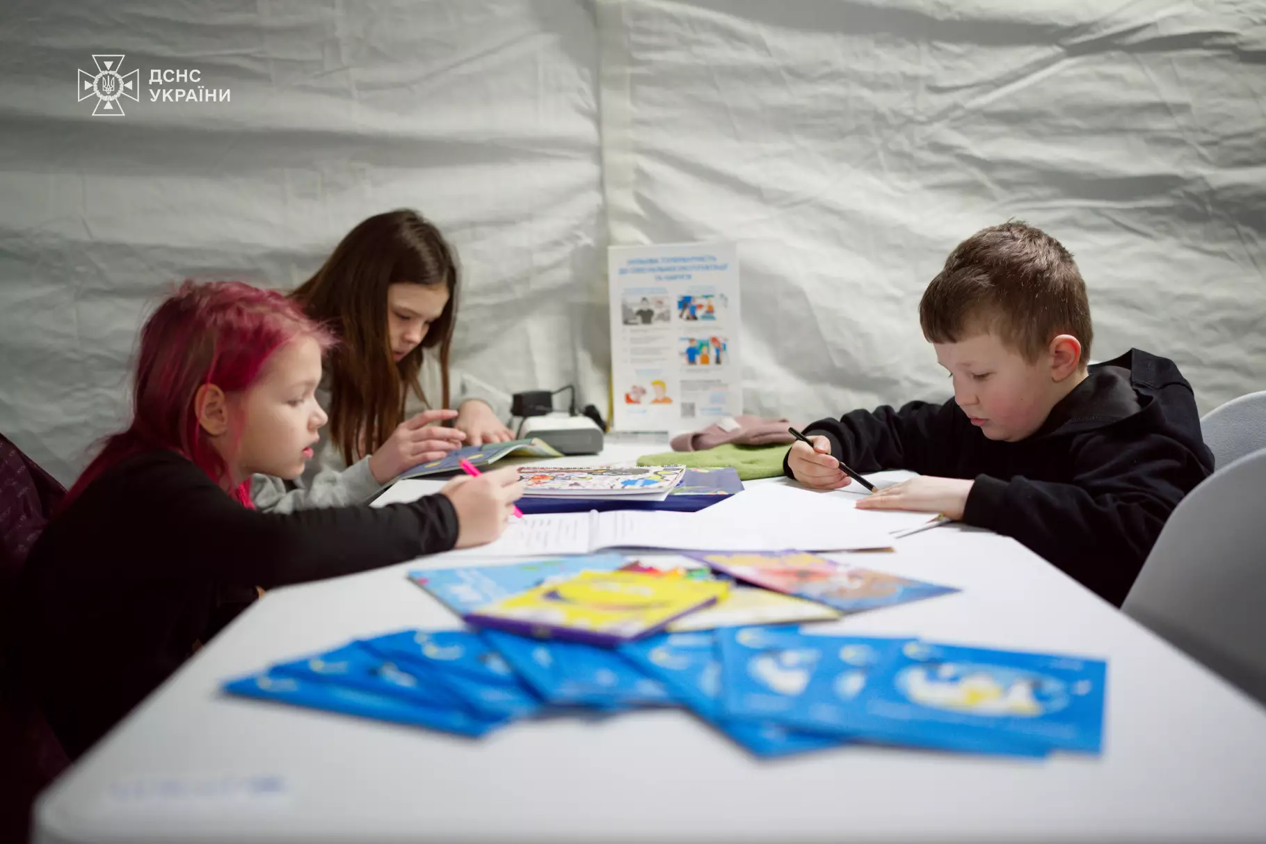 Діти займаються творчістю за столом у мобільному пункті незламності ДСНС та ЮНІСЕФ
