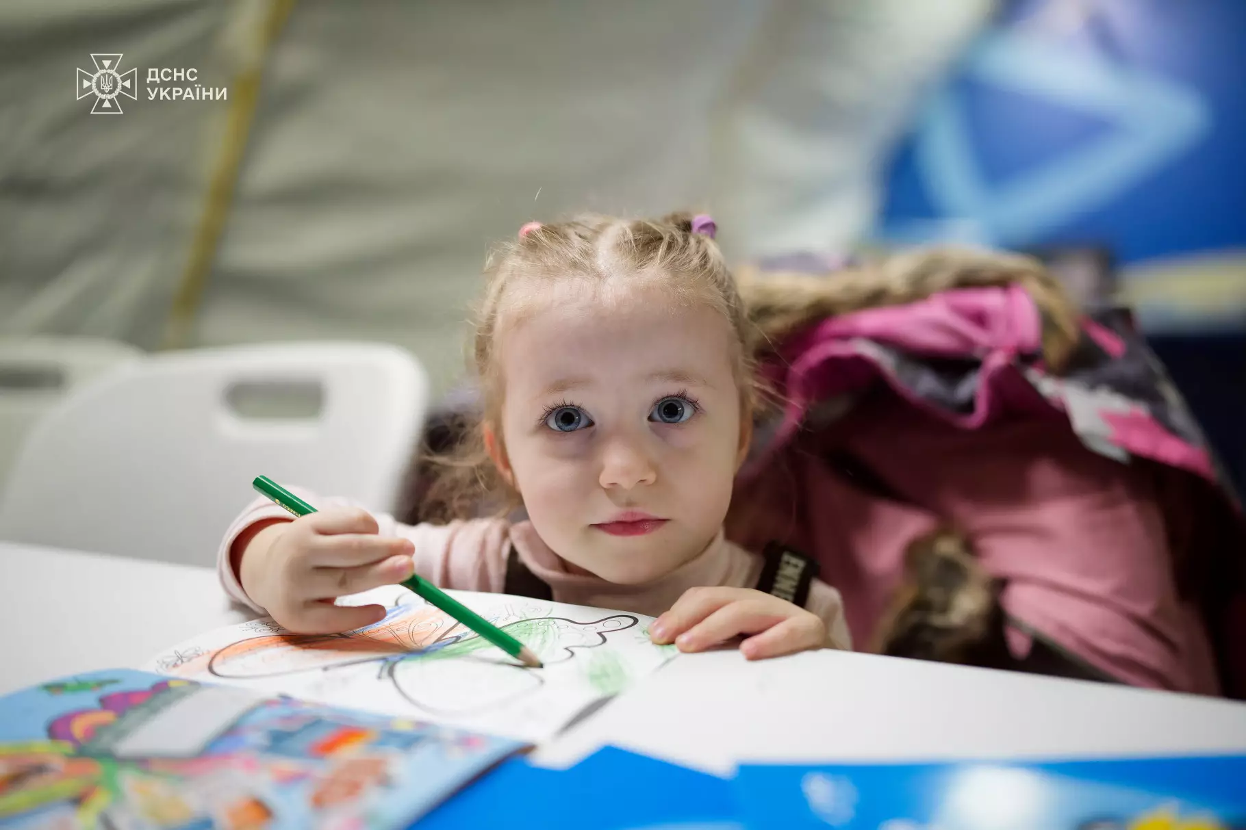 Дівчинка малює за столом у мобільному пункті незламності ДСНС, створеному для психосоціальної підтримки