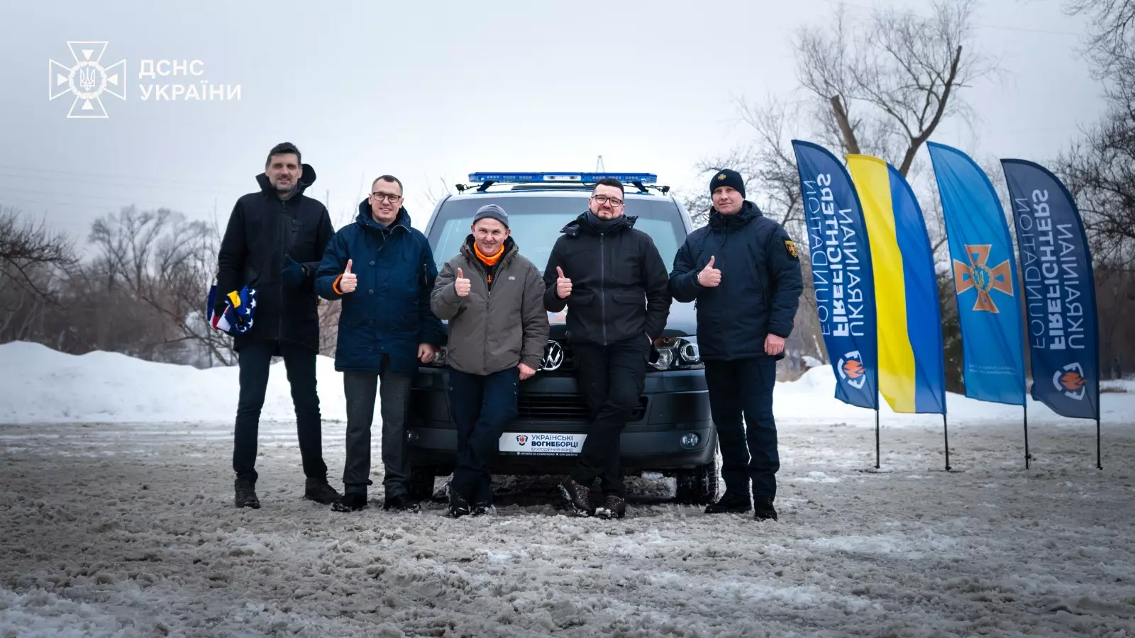 Рятувальники ДСНС України стоять перед броньованим Volkswagen Transporter на церемонії передачі