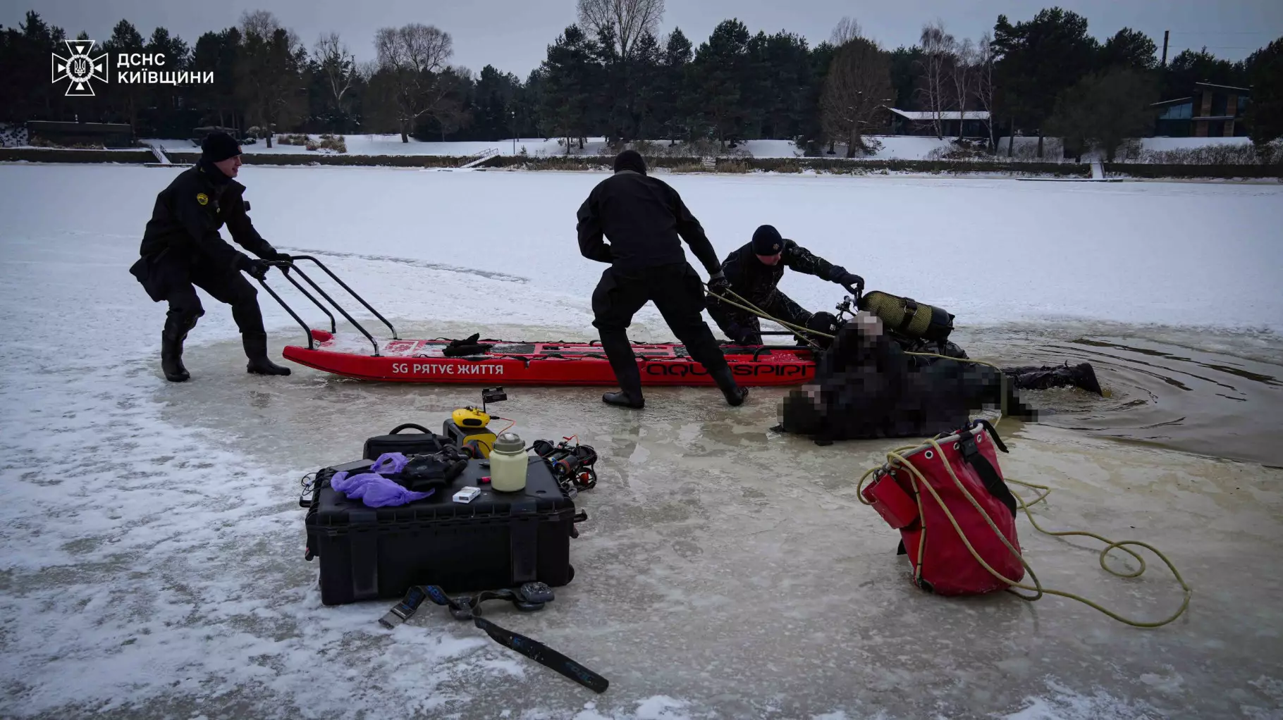 Рятувальники на льоду проводять пошукові роботи біля червоного човна на замерзлій водоймі
