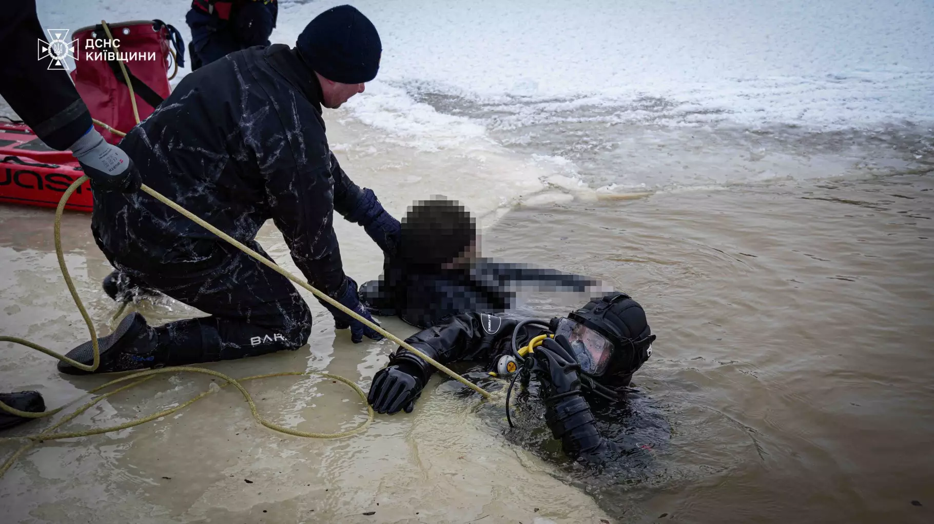 Рятувальники ДСНС України витягують водолаза з крижаної води під час пошукової операції на Київщині