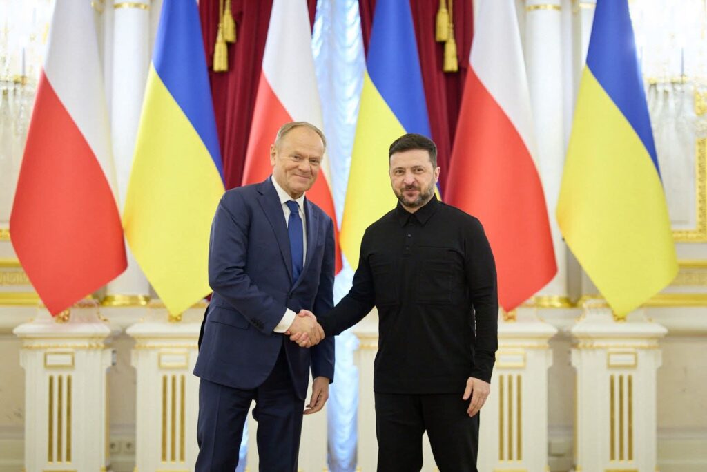 Президент України та Прем’єр-міністр Польщі тиснуть руки на фоні прапорів обох країн