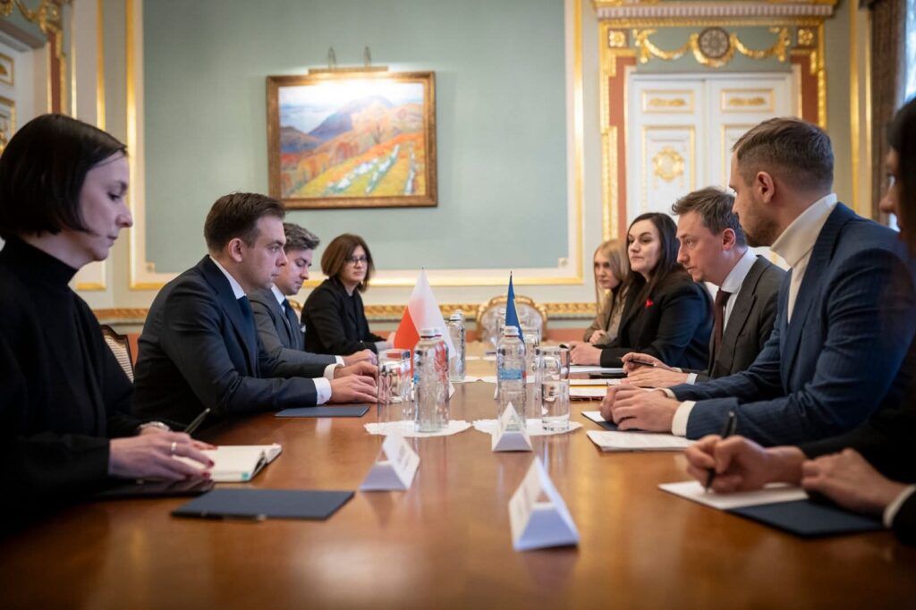 Українська та польська делегації за столом переговорів у розкішній залі з прапорами обох країн