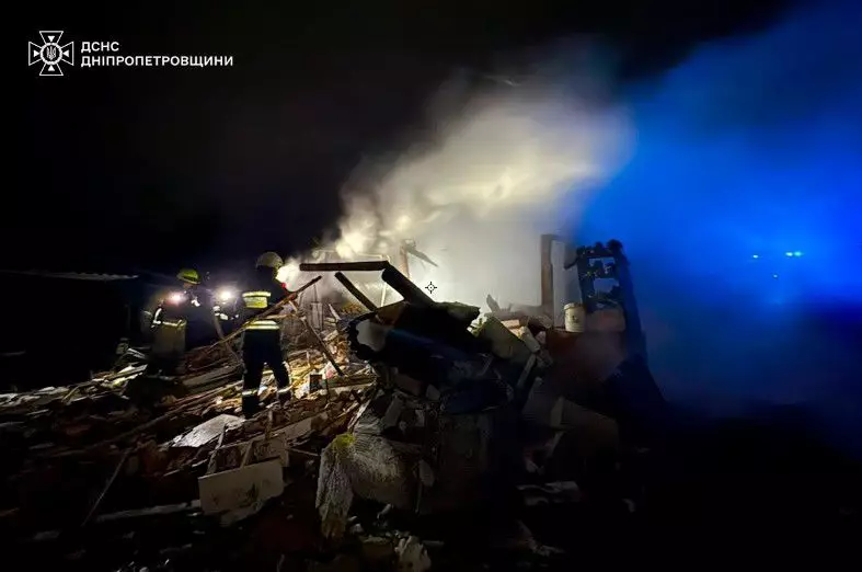 Рятувальники працюють на місці зруйнованої будівлі вночі, дим піднімається вгору, освітлення синє